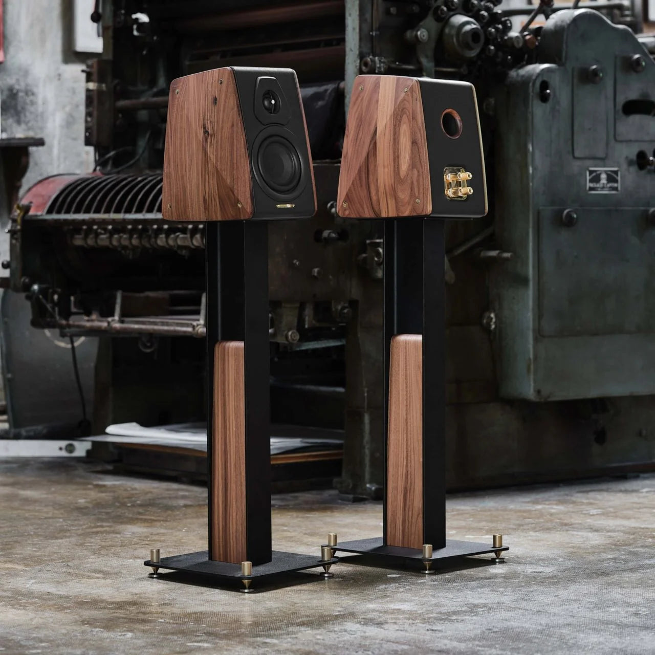 Pair of wooden speakers on stands in an industrial setting