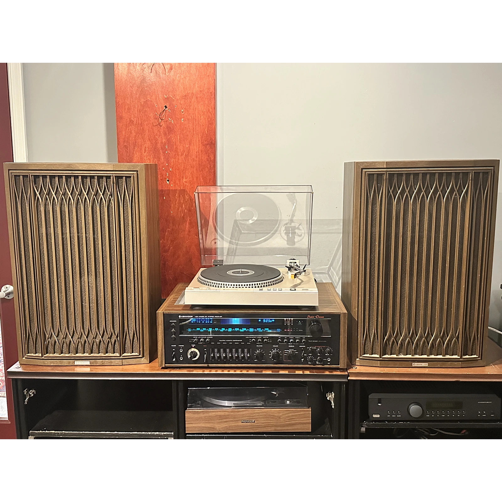 Vintage audio equipment with speakers and a turntable on a wooden cabinet.
