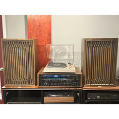 Vintage audio equipment with speakers and a turntable on a wooden cabinet.