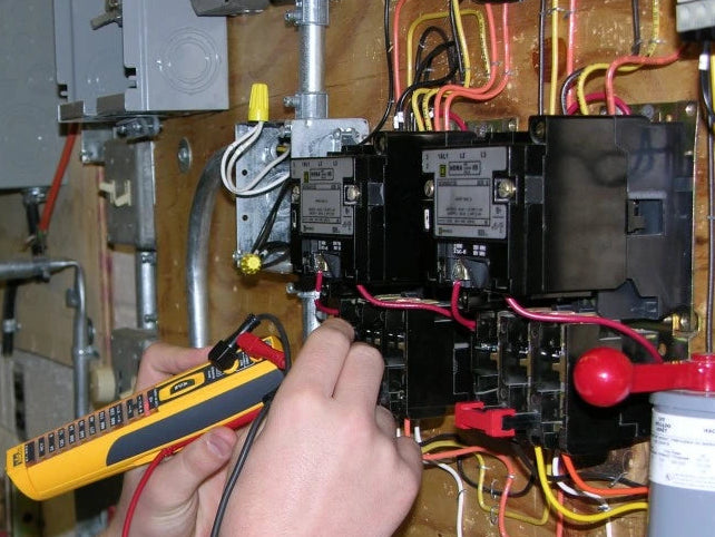 Person working on electrical panel with wires and tools