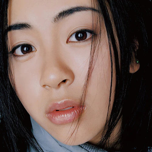Close-up of a person with dark hair and earrings against a blurred background