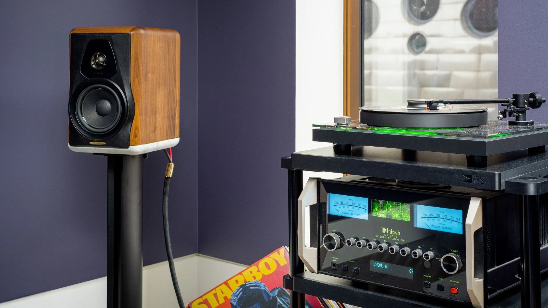 Wooden speaker and turntable setup against a purple wall.
