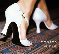 White high-heeled shoes on a patterned rug with 'costes la suite' text.